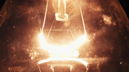 Le filament de tungstène de l'ampoule à incandescence brille et scintille en gros plan au Ralenti