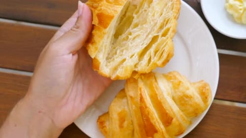 Woman Spreading Butter on Fresh Baked Croissant