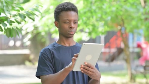 Casual African Man Using a Tablet in a Park