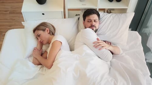 Offended Caucasian Woman Lying on White Pillow Covered with a Blanket