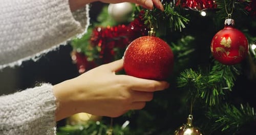 Woman Decorates Christmas Tree With Ornaments at Home