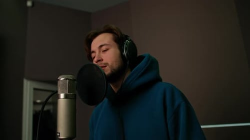 singer with headphones and microphone emotionally recording a new song in a professional studio