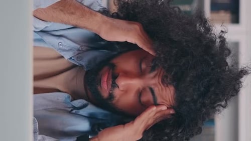 Man Covering Face With Hands in Workplace