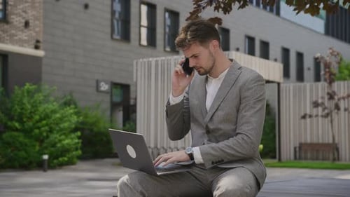 Young Adult Using Laptop and Mobile Phone Outdoors