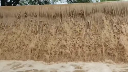 Very fast brown water falling from the dam.