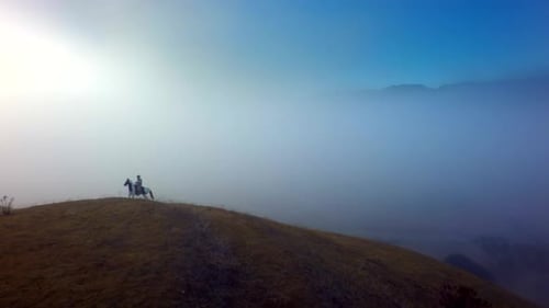 Lone Horseman Riding on Hill in Misty Landscape