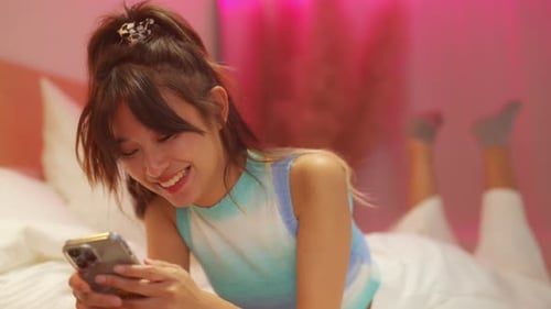 Young Woman Using Phone While Lying on Bed