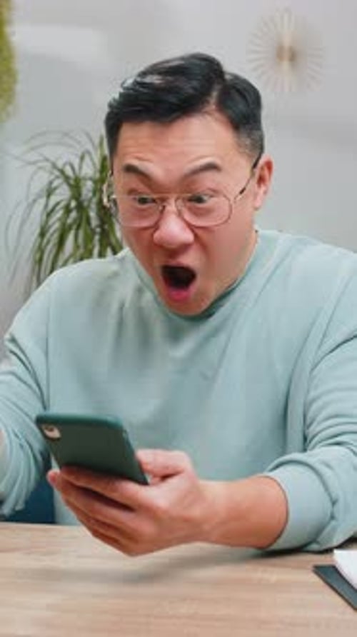 Man Reacts with Joy to Phone in Home Setting