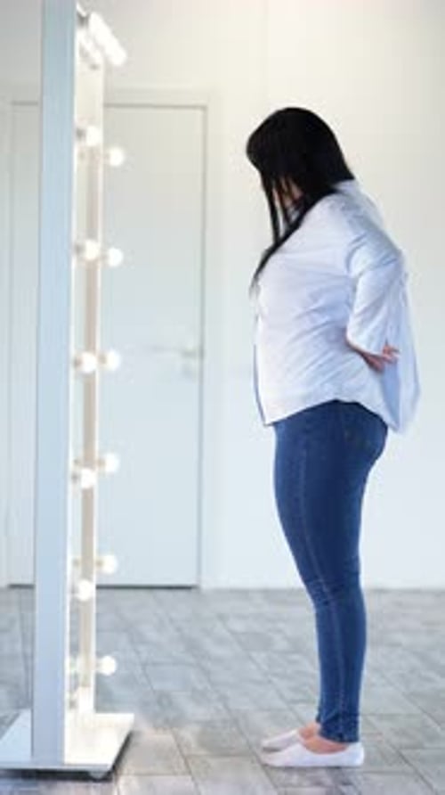 Woman Examining Herself in Lighted Vanity Mirror