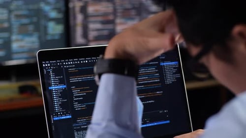 Gros plan du moniteur d'un ordinateur portable montrant la base de données écrite par un homme avec plusieurs moniteurs