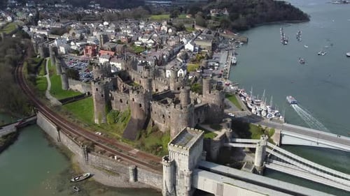 An aerial view of Conwy Castle on a sunny day, flying left to right around the castle with the town