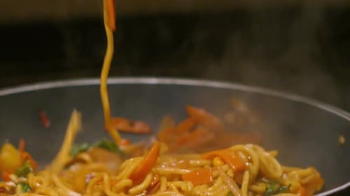 Steaming Noodles with Vegetables Being Stir-Fried Indoors