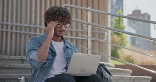 Young Adult Using Laptop on Urban Stairs