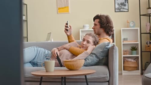 Couple Relaxing on Sofa, Watching Television Together