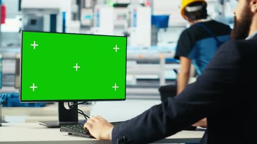Der Arbeiter in der Photovoltaik-Fabrik überwacht die Systemleistung auf einem Greenscreen-PC