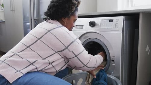 Woman Loads Clothes Into Washing Machine At Home