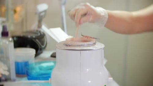 Esthetician Stirring Hot Wax in Salon