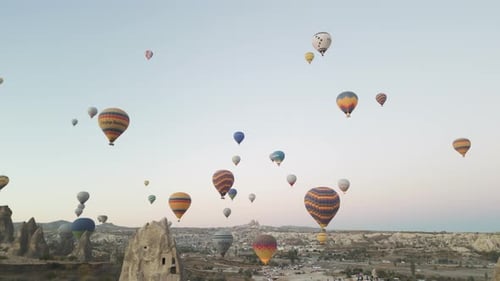 Aerial view of cave homes with hot air balloons in Cappadocia, Turkey.