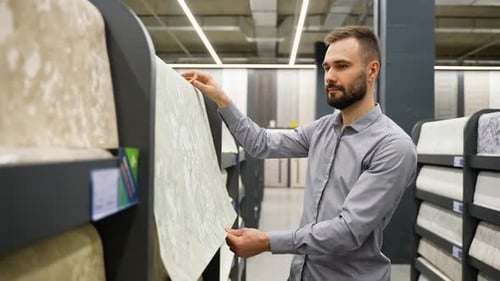A Man Looking Samples of Designer Wallpaper in Household Store