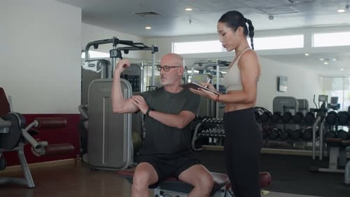 Man Communicating with Fitness Coach during Individual Session in Gym