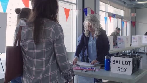 Volunteer Greeting Mother and Daughter Arriving Vote at Polling Place Adult