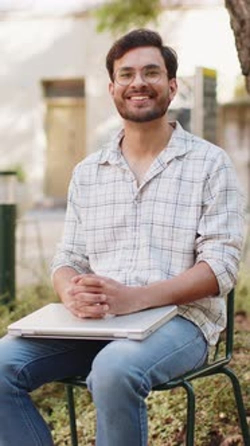 Indian Man Freelancer Sitting on Chair Closes Laptop Screen Finishing Work Smiling in City Outdoors