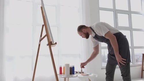 A Talented Artist Using a Brush Creates a Modern Masterpiece of Oil Painting on a White Canvas