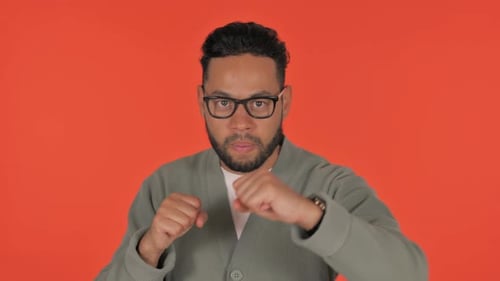 Man with Glasses Boxing in Front of Orange Background