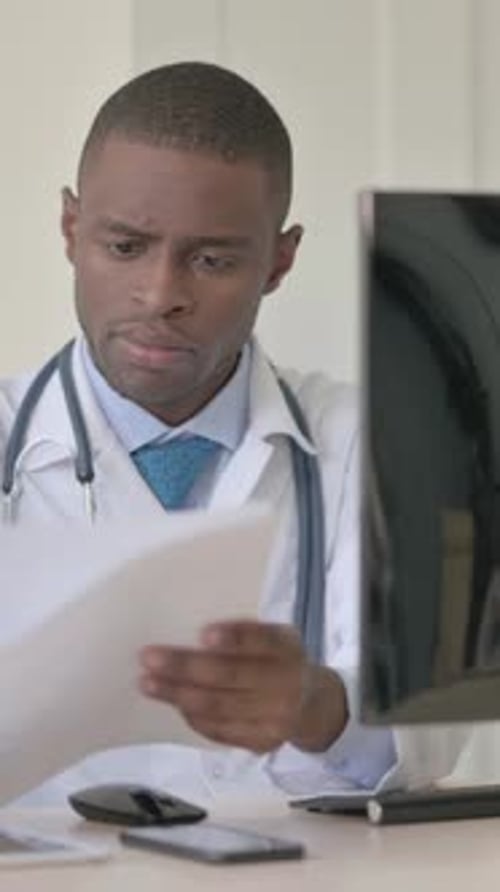 African Doctor Working on Medical Report and Laptop in Clinic, Vertical Video