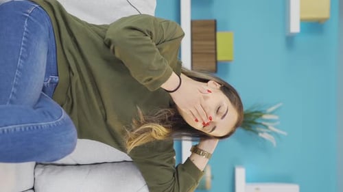 Vertikales Video eines müden und schlaflosen jungen Mädchens, das auf dem Sofa einschläft.