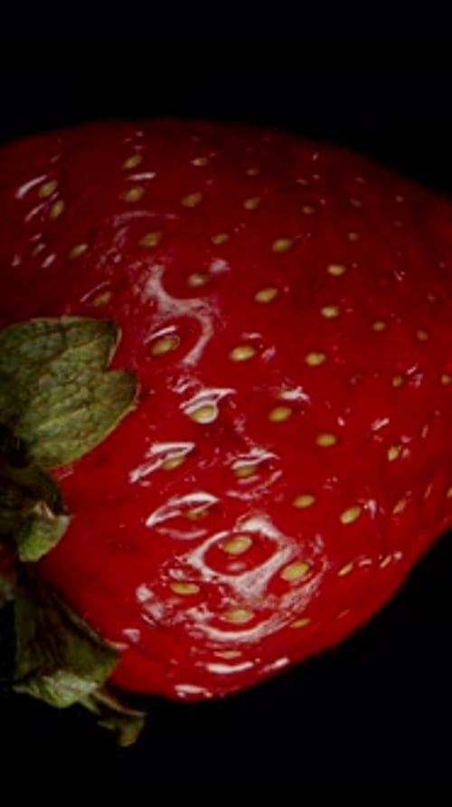 Vertical video. Slow-Motion Fall of a Strawberry and a Hand Catches It, Top View on a Black