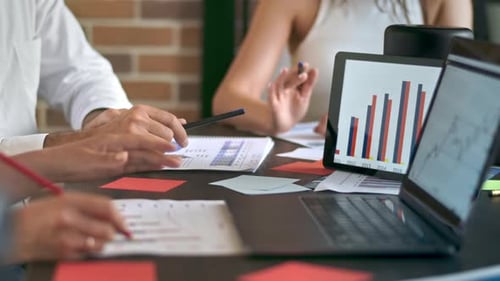 Three people are working and talking in the office. Gadgets and papers with graphs and information