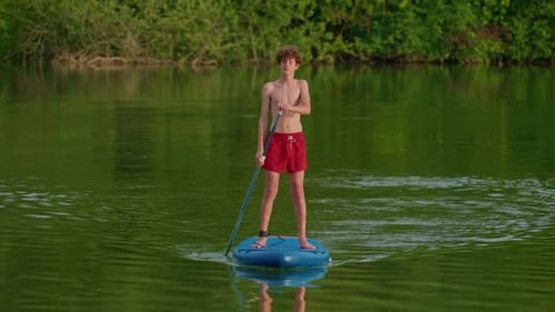 Alone Boy Floating on Stand Up Paddle Board in Lake in Summertime Standup Paddleboarding Surfer Rows