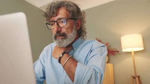 Adult With Gray Hair Using Laptop Indoors
