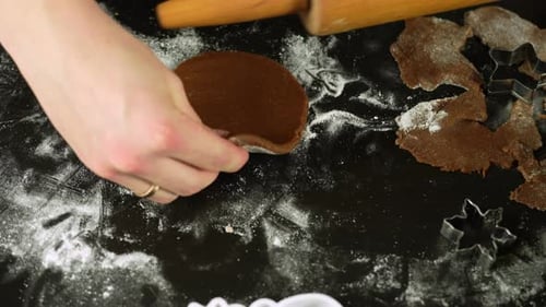 Mother rolling gingerbread dough beside wooden pin, star cookie cutter nearby for cookie preparation