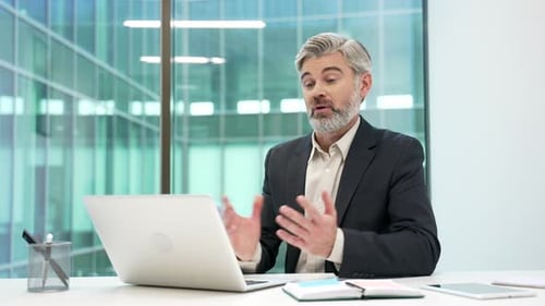 Confident mature businessman talking on a video call conference using laptop in office. The manager