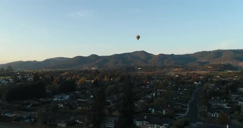 steady Aerial follow shot of hot air balloon rising above town