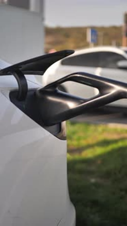 Vertical An Electric Car Charging Via a Cable in a Shopping Mall Parking Lot The Cable with Electric