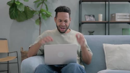 Wütender hispanischer Mann benutzt Laptop frustriert im Schoß
