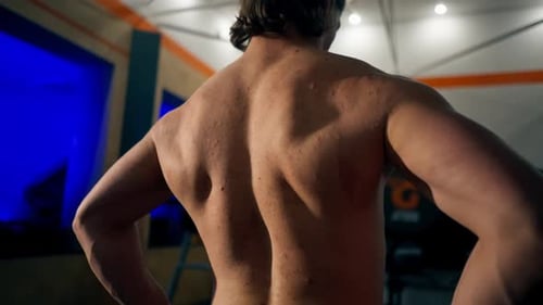 In the Gym Young Handsome Trainer Warms Up His Back Bending and Unbending Demonstrating His Back