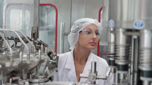 Female worker inspecting water quality and bottle on production line drink water factory