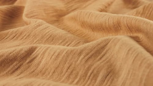 Close-up view of the soft folds of the thin beige cotton jersey cantaloupe shade.