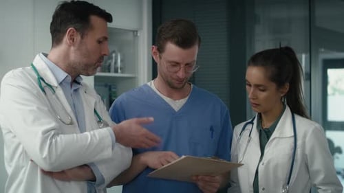 Three serious caucasian doctors discussing over documents in medical clinic. Shot with RED helium ca