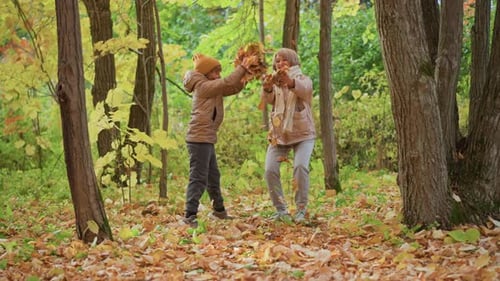 Mother and Daughter Tossing Autumn Leaves Together in Playful Forest Moment