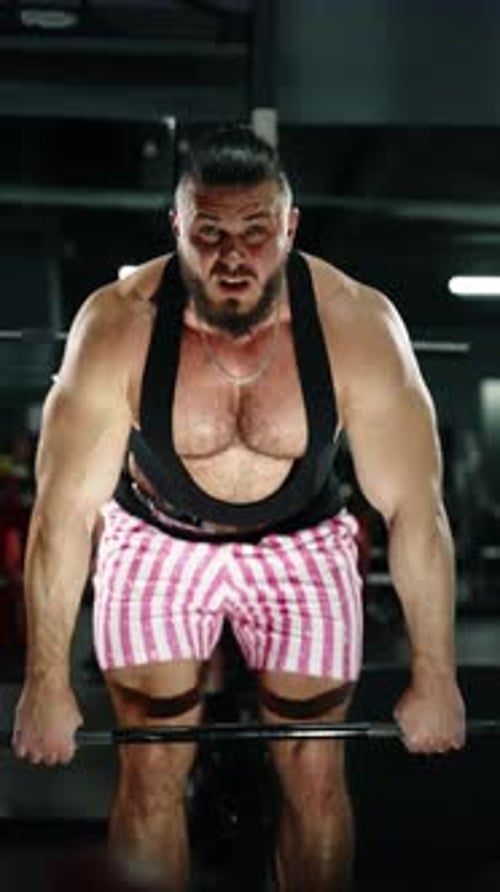 Focused Weightlifter Performing Barbell Bentover Row in Dimly Lit Gym Transitioning From Setup to
