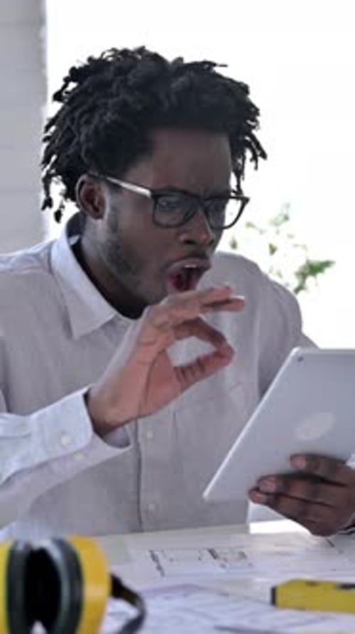 African Engineer Celebrating Success on Tablet, vertical video