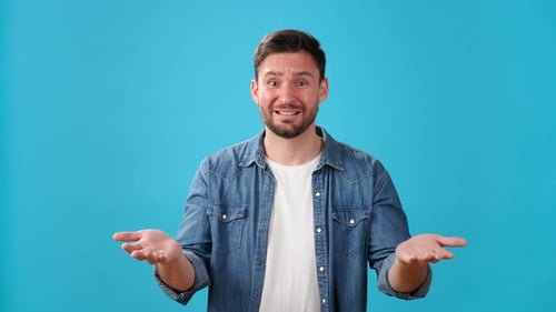 Expressive Man Gesturing in Studio Against Blue Background