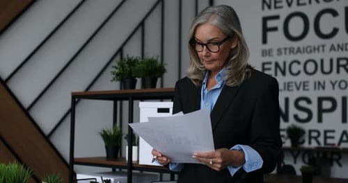 Caucasian Middle Aged Older Businesswoman Checking Reports in Documents in Modern Office Small