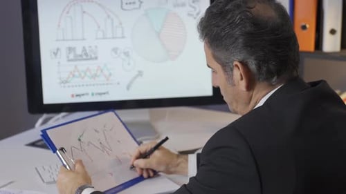Reifer Geschäftsmann analysiert Grafiken in seinem Büro. Grafiken zum Periodengewinn oder -verlust, Statistiken.
