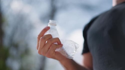 Person Holding Discarded Plastic Bottle In Park Environment Individual Demonstrating Ecological